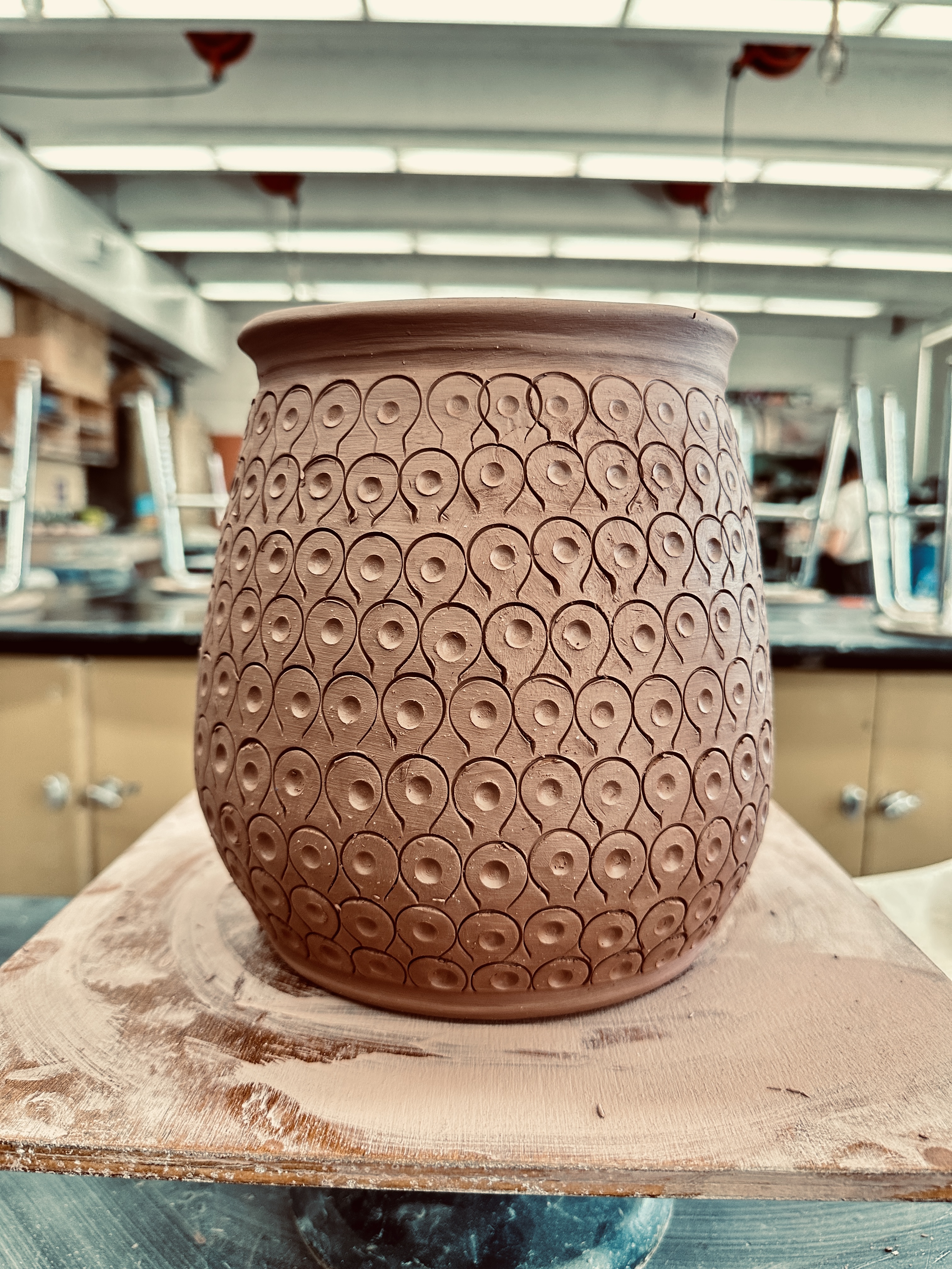 A thown greenware pot, it's in the leatherhard stage and patterned with a wire end clay tool and wooden modeling mool.